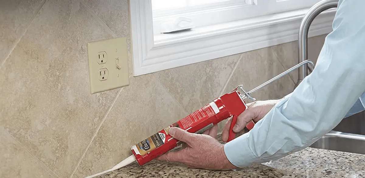 Handyman applying caulk along a kitchen backsplash and countertop seam in West Palm Beach, FL